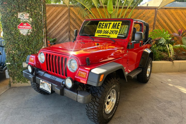 Red Jeep with a 'Rent Me' sign parked outdoors.