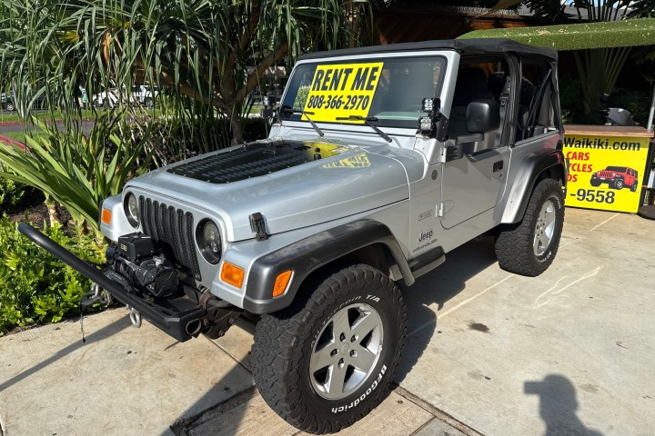 Silver Jeep with 'Rent Me' sign parked outdoors.